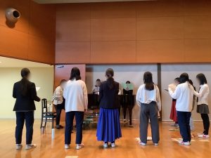 クラブメンバーが声楽のコーチの指導を受けながら合唱をしている様子